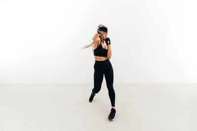 Full length of young woman photographing against white background