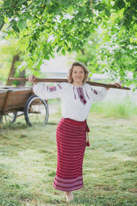 Portrait of young woman standing against trees