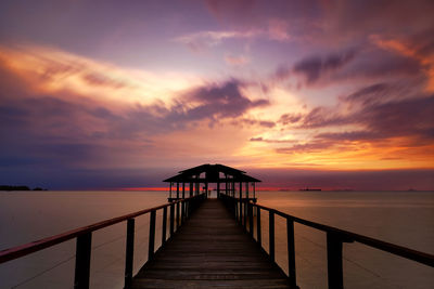 Pier on sea against romantic sky at sunset