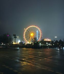 Illuminated ferris wheel against clear sky at night