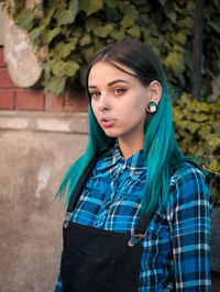 Portrait of young woman standing against tree