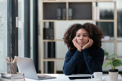 Portrait of young woman using laptop at table