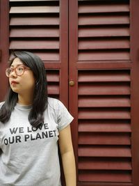 Young woman looking away while standing against closed shutter
