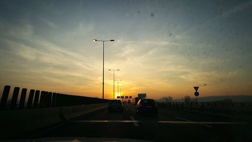 Cars on road against sky during sunset