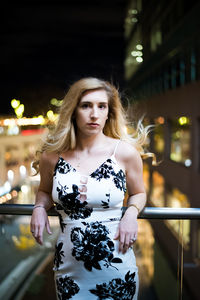 Portrait of young woman against illuminated lights