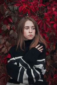 Portrait of young woman standing amidst plants