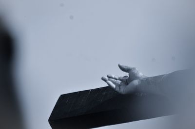 Cropped hand of person with nail on wood against wall