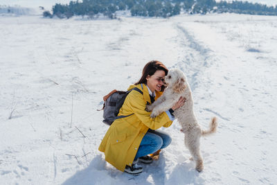 Woman with dog on snowcapped mountain against sky