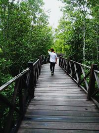 Rear view of woman walking on footbridge