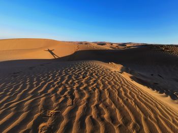 Scenic view of desert against clear blue sky