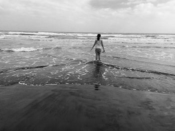 Woman standing on beach against sky