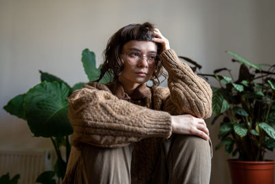 Portrait of young woman standing against plants