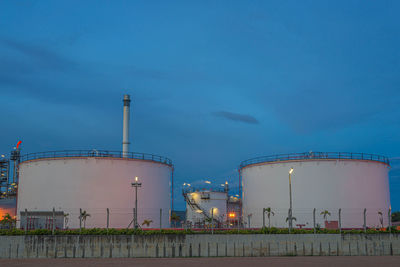 Illuminated factory against sky at dusk