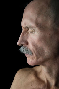 Close-up of a young man looking away over black background