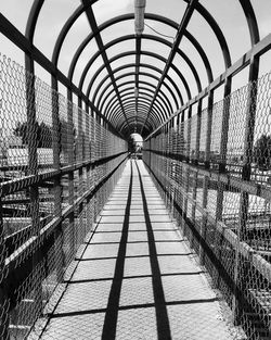 Empty long footbridge against sky