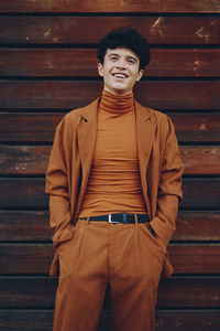 Portrait of young woman standing against wall
