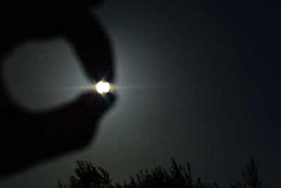 Close-up of illuminated candle in darkroom against sky