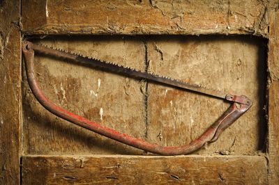 Close-up of rusty hand saw on dirty wooden niche