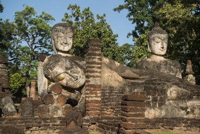 Buddha statue by tree against temple