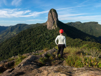 Rear view of woman standing on mountain against sky