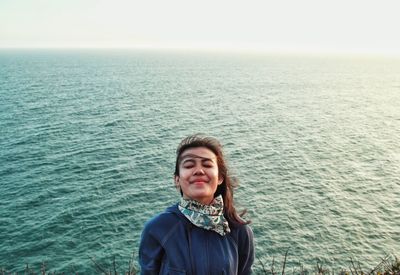 Portrait of smiling woman standing in sea against sky