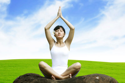 Woman doing yoga against sky