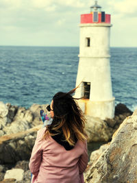 Rear view of woman looking at sea shore against sky