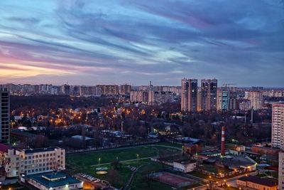 High angle view of city lit up against cloudy sky