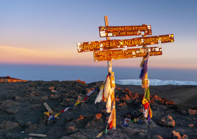 Information sign on shore against sky during sunset