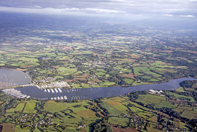 Aerial view of agricultural field by river against sky