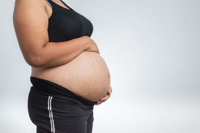 Midsection of woman touching hair against white background