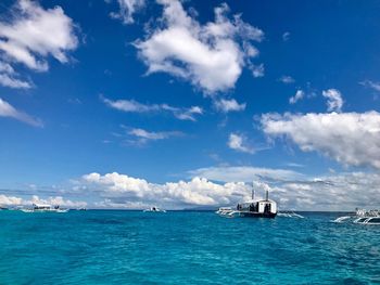 Boats sailing in sea against blue sky