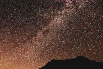 Low angle view of silhouette mountain against sky at night