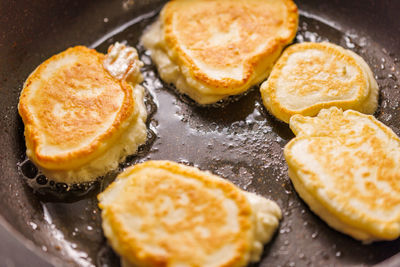 Pancakes frying on skillet with vegetable oil