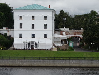 Building by river in town against sky