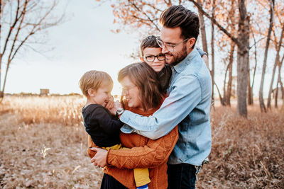 Fashionable young family hugging in a field on a cool autumn evening