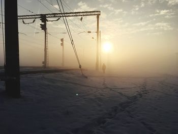 Snow covered landscape against sky during sunset