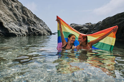 Two lesbians inside the sea with the gay flag. gay concept