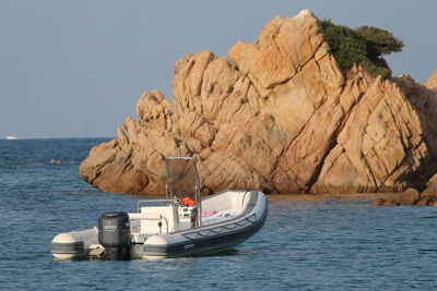 Sailboat sailing on rock by sea against clear sky