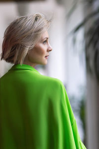 Caucasian blonde in bright green fashionable clothing poses in front of the camera.