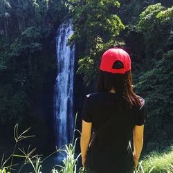 Rear view of woman standing against waterfall