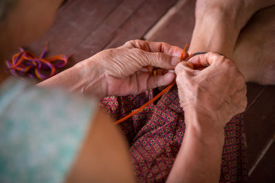 Midsection of woman holding thread while stitching clothes at home