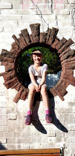 Portrait of teenage girl sitting on stone wall