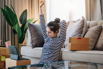 Rear view of woman sitting on sofa at home