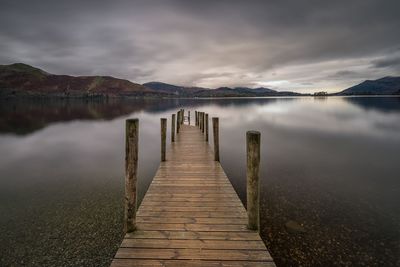 Wooden pier over lake against sky