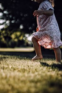 Low section of girl walking on grassy field
