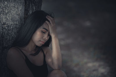 Portrait of a young woman looking away against wall