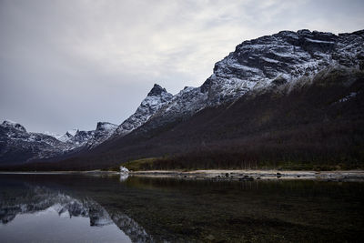 Scenic view of lake by snowcapped mountains against sky