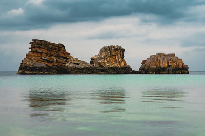 Rock formations in sea against sky