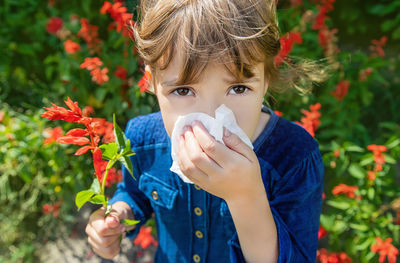 Portrait of sick girl having allergy wiping nose